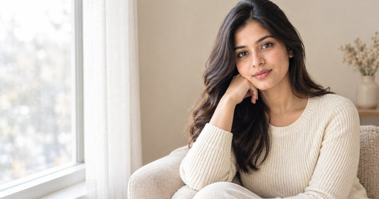 Woman in a cream knit sweater sitting by a window in soft winter light